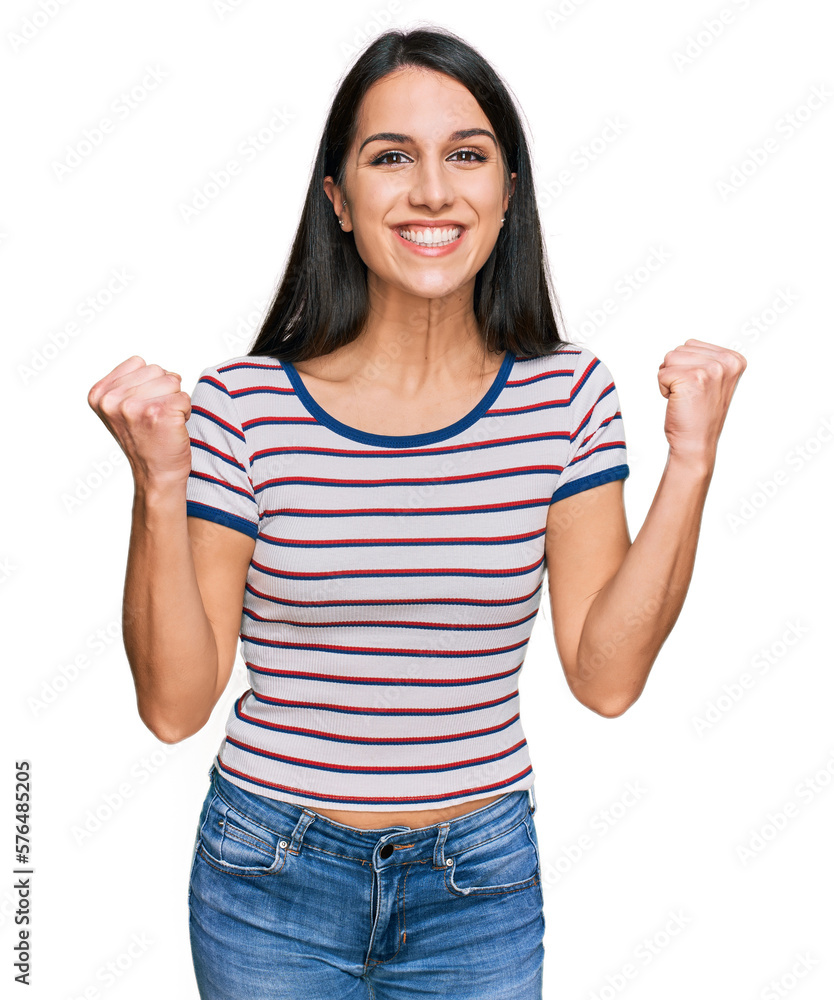 Young hispanic girl wearing casual striped t shirt celebrating surprised and amazed for success with arms raised and open eyes. winner concept. Young hispanic girl wearing casual striped t shirt celebrating surprised and amazed for success with arms raised and open eyes. winner concept.