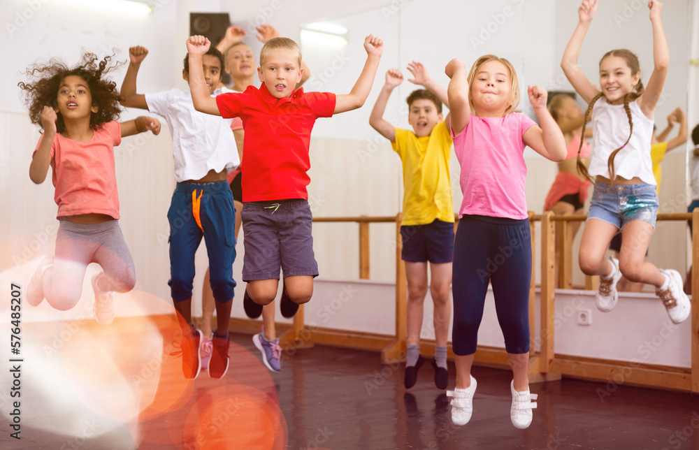 Group of cheerful children dancing and jumping in dance studio during class