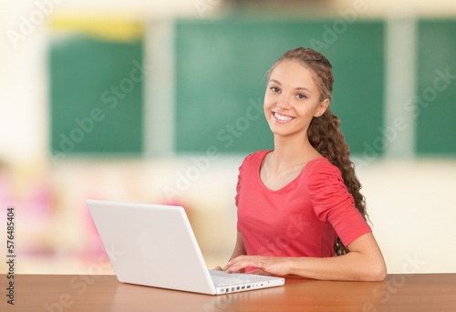 Young happy student sitting at desk with computer