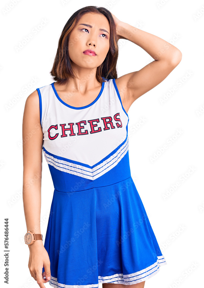 Young beautiful chinese girl wearing cheerleader uniform confuse and wondering about question. uncertain with doubt, thinking with hand on head. pensive concept. Young beautiful chinese girl wearing cheerleader uniform confuse and wondering about question. uncertain with doubt, thinking with hand on head. pensive concept.