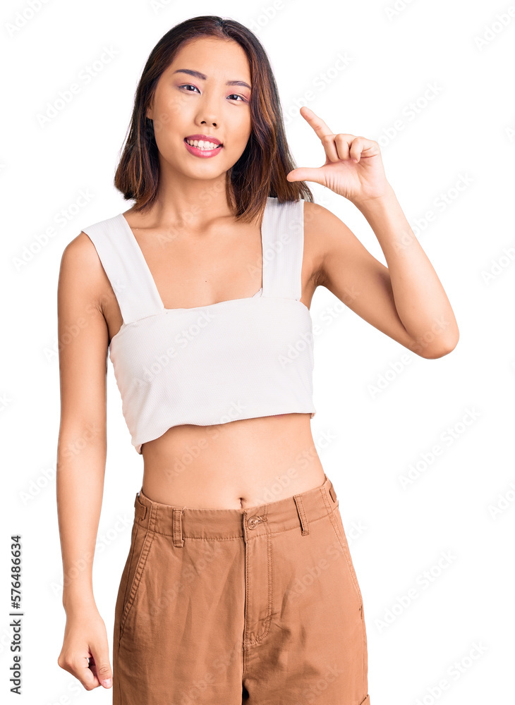Young beautiful chinese girl wearing casual clothes smiling and confident gesturing with hand doing small size sign with fingers looking and the camera. measure concept. Young beautiful chinese girl wearing casual clothes smiling and confident gesturing with hand doing small size sign with fingers looking and the camera. measure concept.