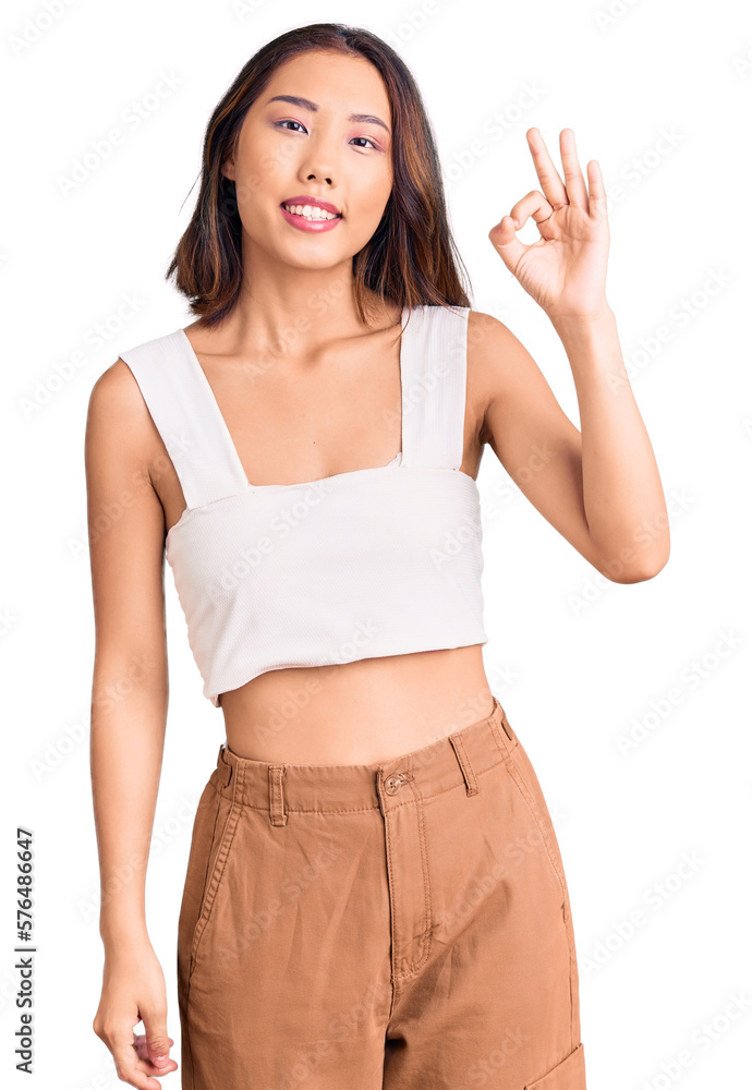 Young beautiful chinese girl wearing casual clothes smiling positive doing ok sign with hand and fingers. successful expression. Young beautiful chinese girl wearing casual clothes smiling positive doing ok sign with hand and fingers. successful expression.