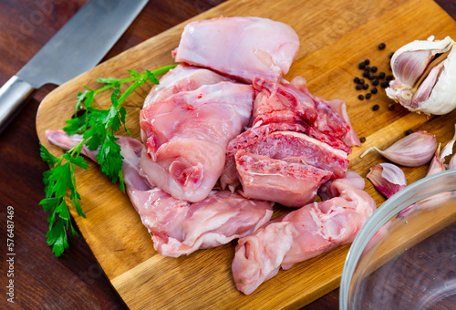 Image of raw rabbit meat with garlic and greens during cooking