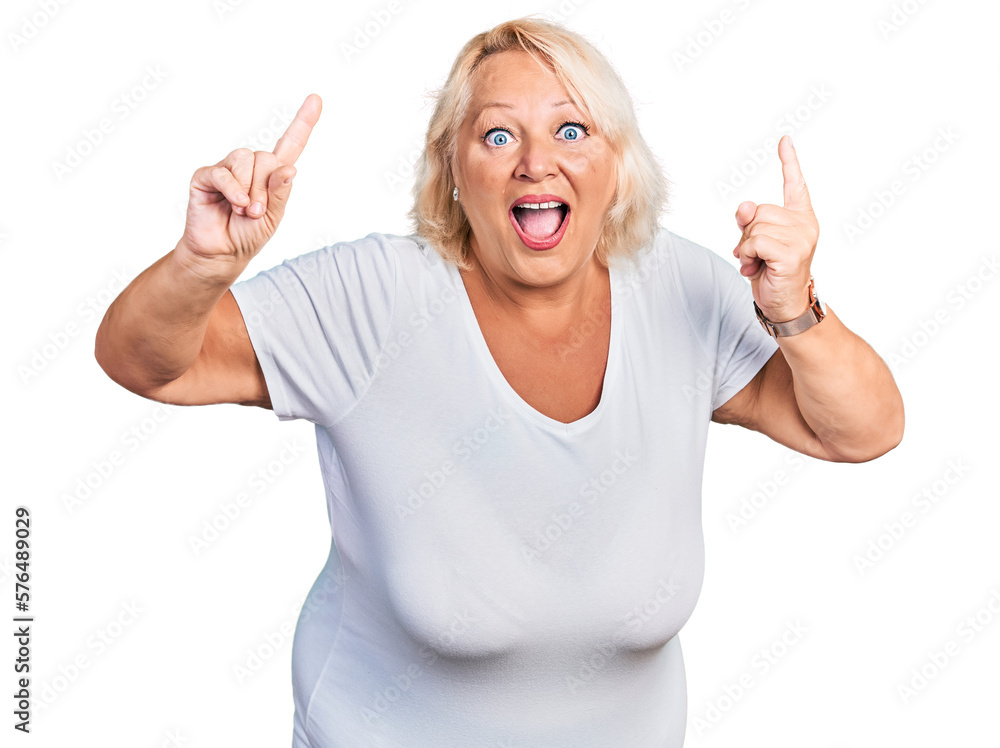 Middle age blonde woman wearing casual white t shirt smiling amazed and surprised and pointing up with fingers and raised arms. Middle age blonde woman wearing casual white t shirt smiling amazed and surprised and pointing up with fingers and raised arms.
