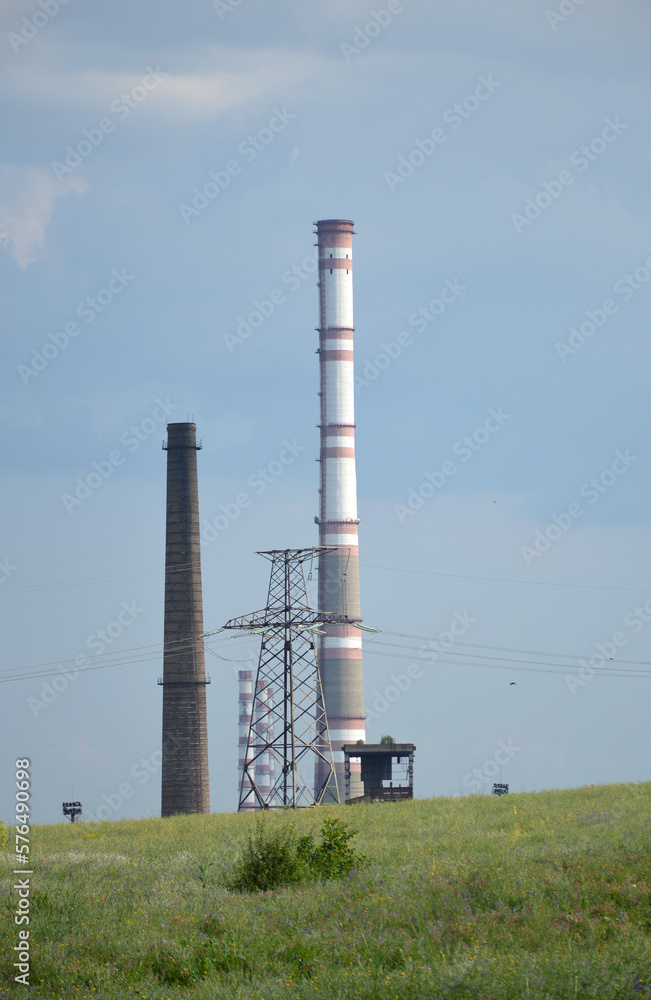 CHP building, power lines and a tall chimney. air emissions and air pollution. abandonment of thermal power plants in favor of the environment, transition to green energy CHP building, power lines and a tall chimney. air emissions and air pollution. abandonment of thermal power plants in favor of the environment, transition to green energy