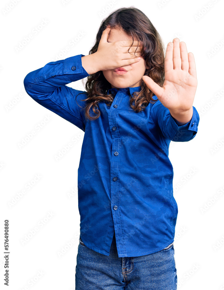 Cute child with long hair wearing casual clothes covering eyes with hands and doing stop gesture with sad and fear expression. embarrassed and negative concept. Cute child with long hair wearing casual clothes covering eyes with hands and doing stop gesture with sad and fear expression. embarrassed and negative concept.