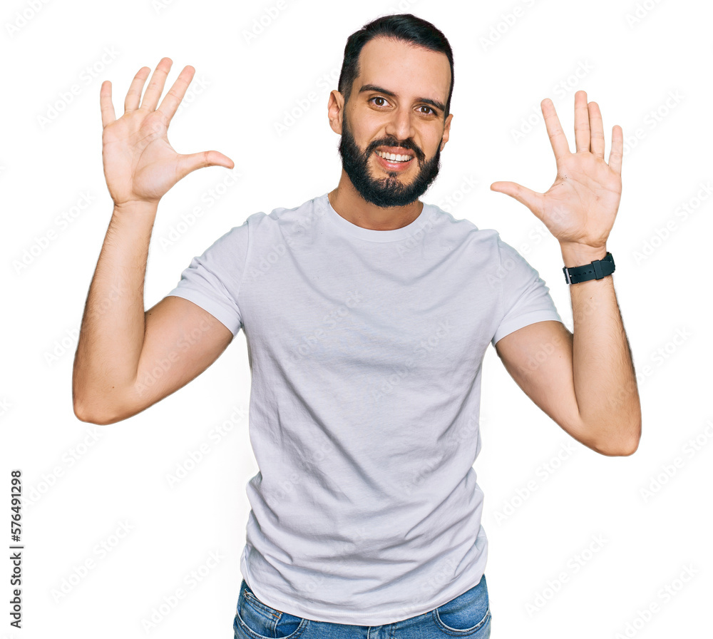 Young man with beard wearing casual white t shirt showing and pointing up with fingers number ten while smiling confident and happy. Young man with beard wearing casual white t shirt showing and pointing up with fingers number ten while smiling confident and happy.