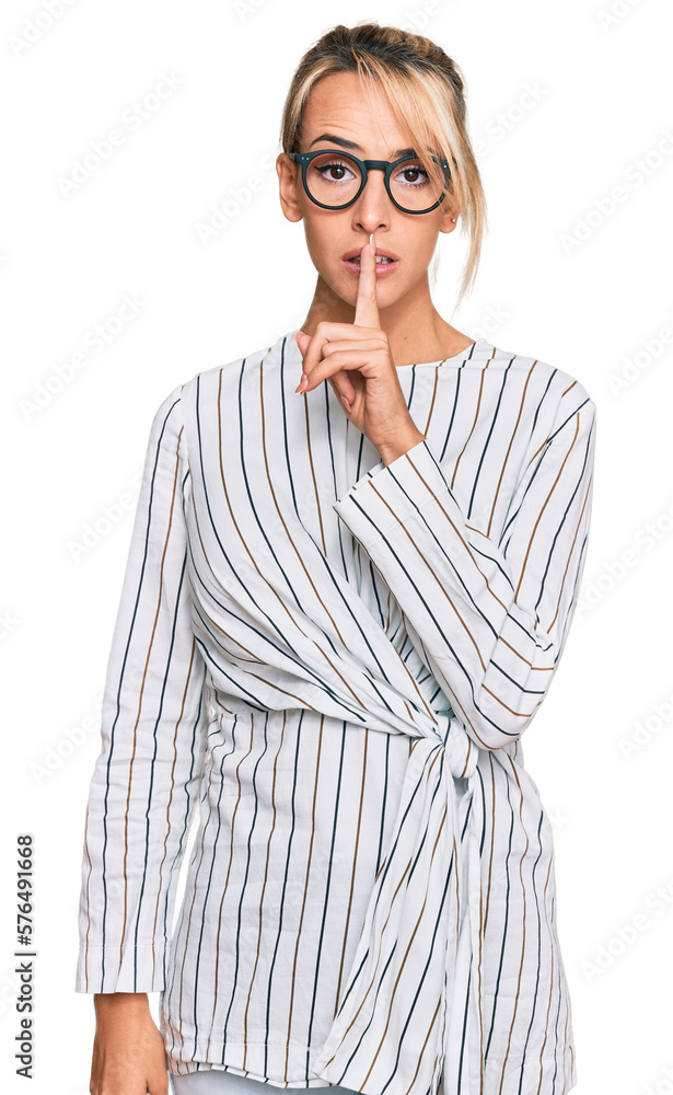 Beautiful blonde woman wearing business shirt and glasses asking to be quiet with finger on lips. silence and secret concept. Beautiful blonde woman wearing business shirt and glasses asking to be quiet with finger on lips. silence and secret concept.