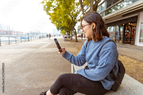 Bild auf Leinwand Joven mujer, con mochila, auriculares, usando el celular, telefono