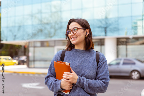 Joven mujer, con mochila, auriculares, preparada para comenzar la universidad. Fotografía plano medio.