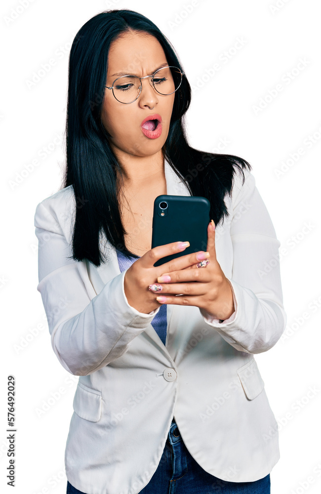 Beautiful hispanic woman with nose piercing using smartphone typing message in shock face, looking skeptical and sarcastic, surprised with open mouth Beautiful hispanic woman with nose piercing using smartphone typing message in shock face, looking skeptical and sarcastic, surprised with open mouth