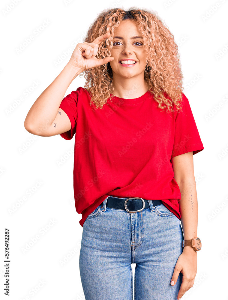 Young blonde woman with curly hair wearing casual red tshirt smiling and confident gesturing with hand doing small size sign with fingers looking and the camera. measure concept. Young blonde woman with curly hair wearing casual red tshirt smiling and confident gesturing with hand doing small size sign with fingers looking and the camera. measure concept.
