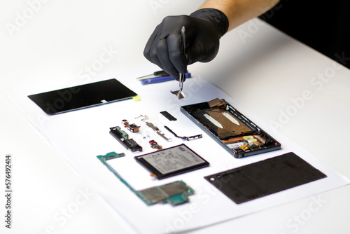 Repairman. Defocus technician repairing the smartphone's motherboard in the lab. Mobile phone, electronic, repairing, upgrade and technology. Disassembling components broken smartphone photo