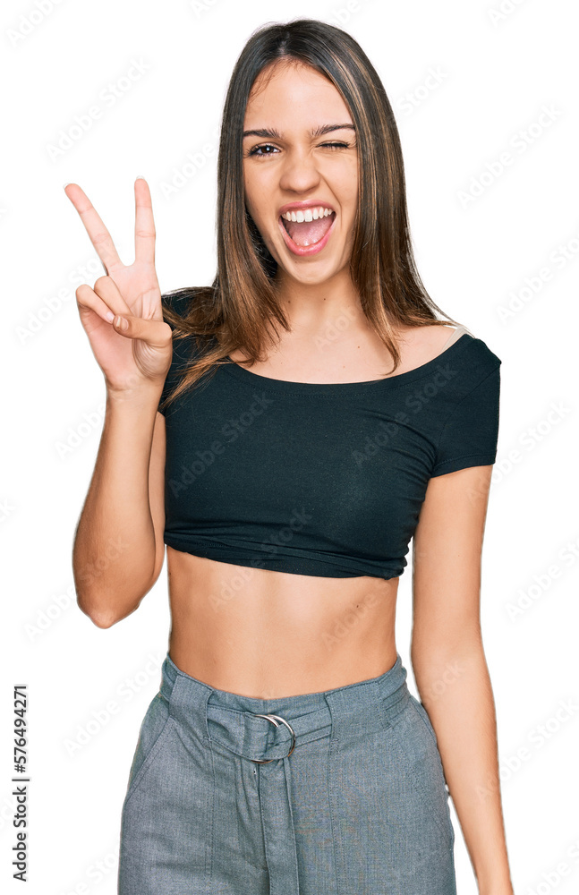 Young brunette woman wearing casual clothes smiling with happy face winking at the camera doing victory sign. number two. Young brunette woman wearing casual clothes smiling with happy face winking at the camera doing victory sign. number two.