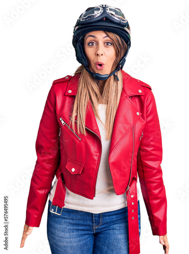 Young beautiful woman wearing motorcycle helmet scared and amazed with open mouth for surprise, disbelief face © Krakenimages.com