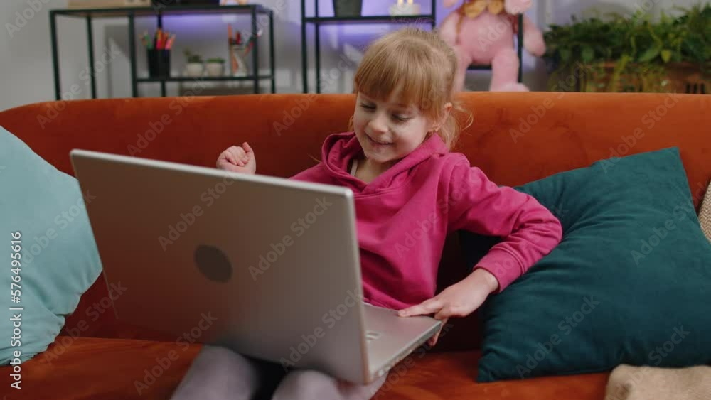 Young child kid girl use laptop making video webcam conference call with friends or family, enjoying pleasant conversation. Female teen toddler laughing, waving hello at home in room sits on sofa Young child kid girl use laptop making video webcam conference call with friends or family, enjoying pleasant conversation. Female teen toddler laughing, waving hello at home in room sits on sofa