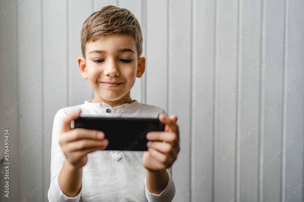 One caucasian boy child use smartphone mobile phone at home play games One caucasian boy child use smartphone mobile phone at home play games