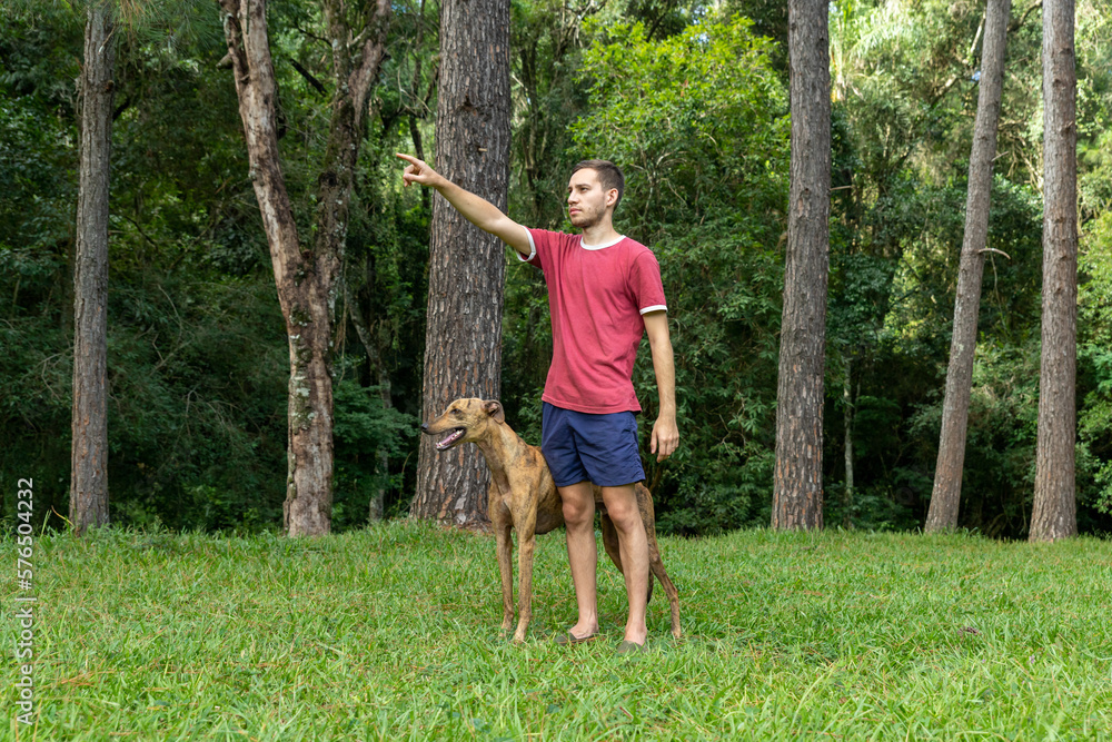 hombre joven, caucasico, con un perro galgo, disfrutando al aire libre. hombre joven, caucasico, con un perro galgo, disfrutando al aire libre.