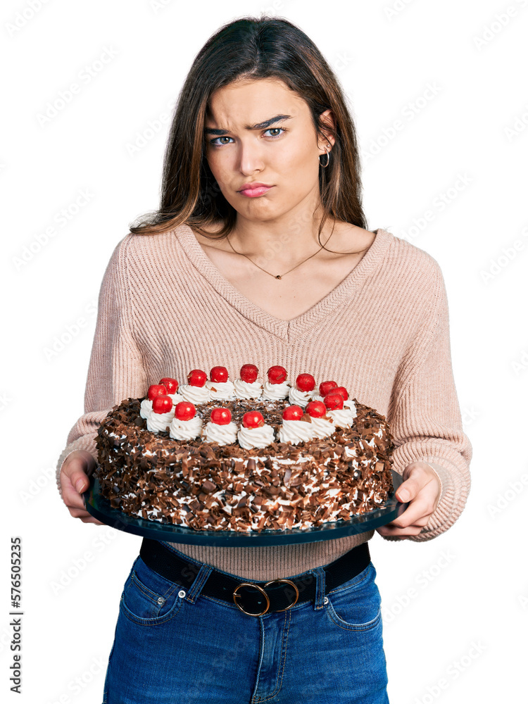 Young caucasian girl celebrating birthday holding big chocolate cake depressed and worry for distress, crying angry and afraid. sad expression. Young caucasian girl celebrating birthday holding big chocolate cake depressed and worry for distress, crying angry and afraid. sad expression.