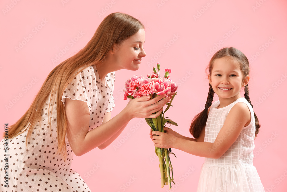 Cute little girl greeting her mother with flowers on pink background Cute little girl greeting her mother with flowers on pink background
