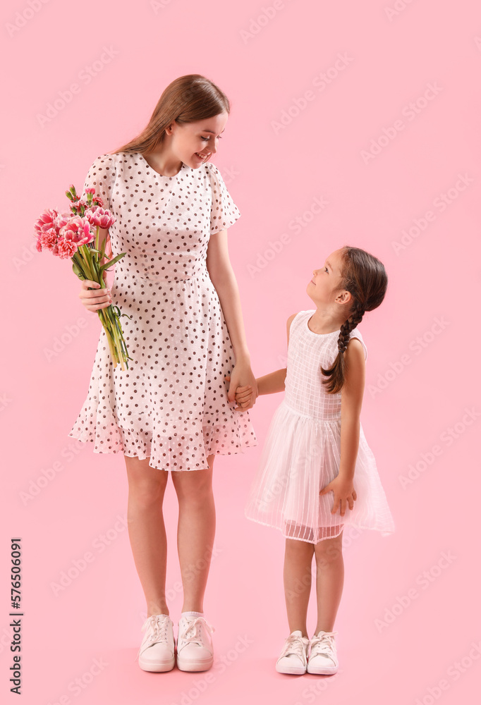Cute little girl and her mother with flowers holding hands on pink background Cute little girl and her mother with flowers holding hands on pink background