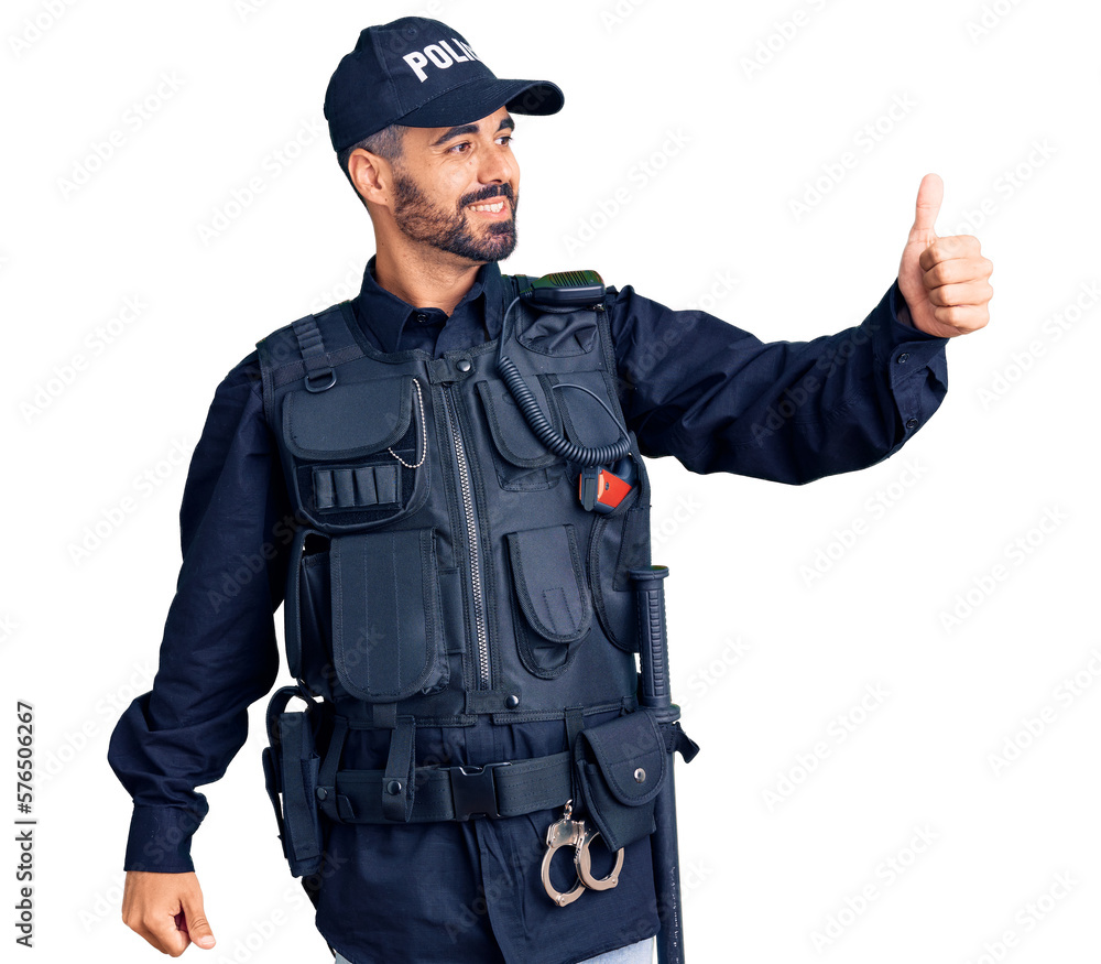 Young hispanic man wearing police uniform looking proud, smiling doing thumbs up gesture to the side Young hispanic man wearing police uniform looking proud, smiling doing thumbs up gesture to the side