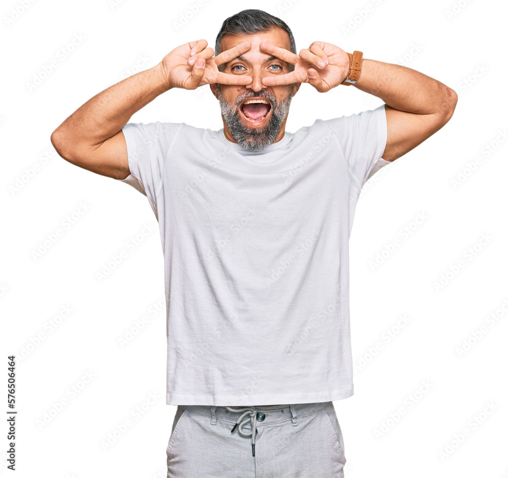Middle age handsome man wearing casual white tshirt doing peace symbol with fingers over face, smiling cheerful showing victory Middle age handsome man wearing casual white tshirt doing peace symbol with fingers over face, smiling cheerful showing victory