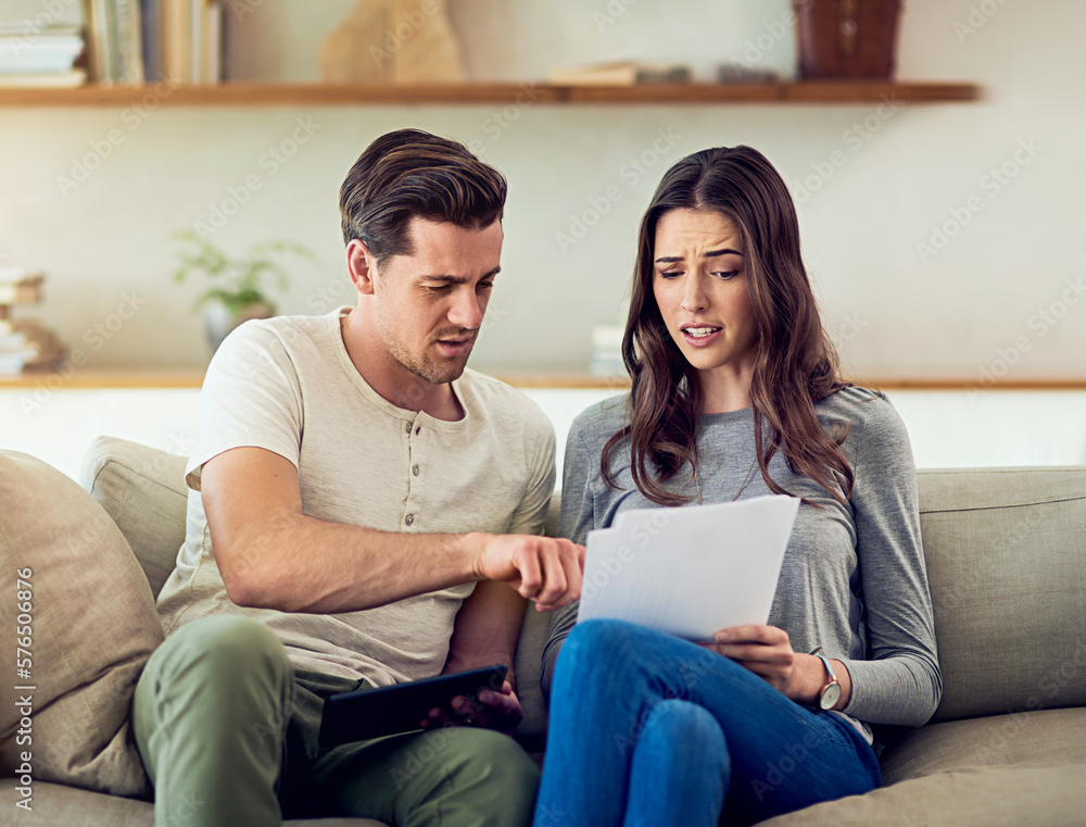 Our spending is starting to get out of hand. Shot of a young couple going through their paperwork together at home and looking worried. Our spending is starting to get out of hand. Shot of a young couple going through their paperwork together at home and looking worried.