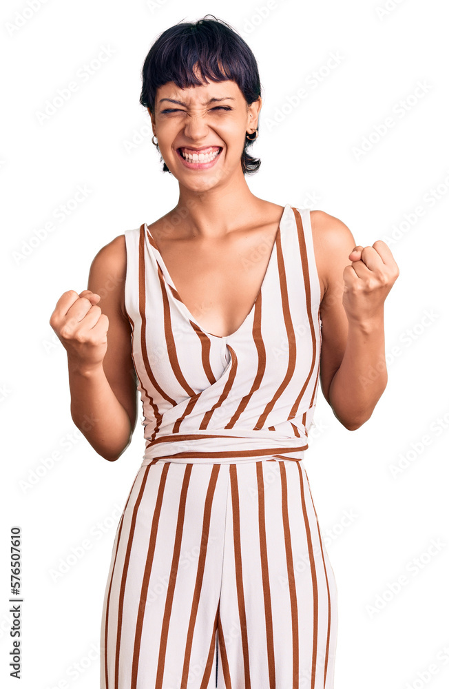 Young brunette woman with short hair wearing summer outfit excited for success with arms raised and eyes closed celebrating victory smiling. winner concept. Young brunette woman with short hair wearing summer outfit excited for success with arms raised and eyes closed celebrating victory smiling. winner concept.