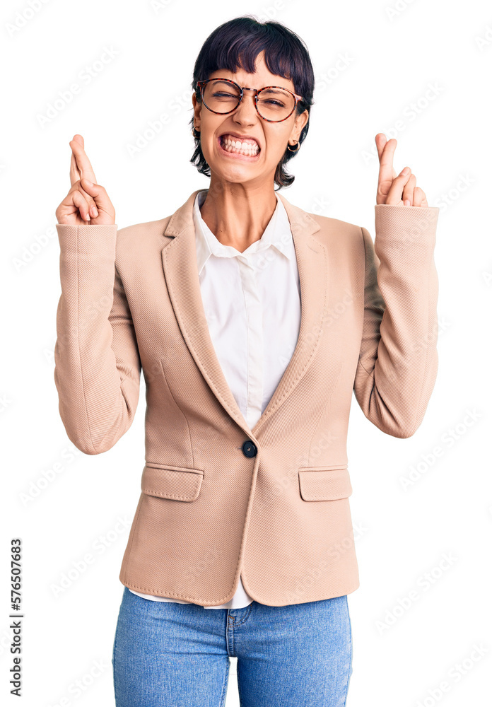 Young brunette woman with short hair wearing business jacket and glasses gesturing finger crossed smiling with hope and eyes closed. luck and superstitious concept. Young brunette woman with short hair wearing business jacket and glasses gesturing finger crossed smiling with hope and eyes closed. luck and superstitious concept.