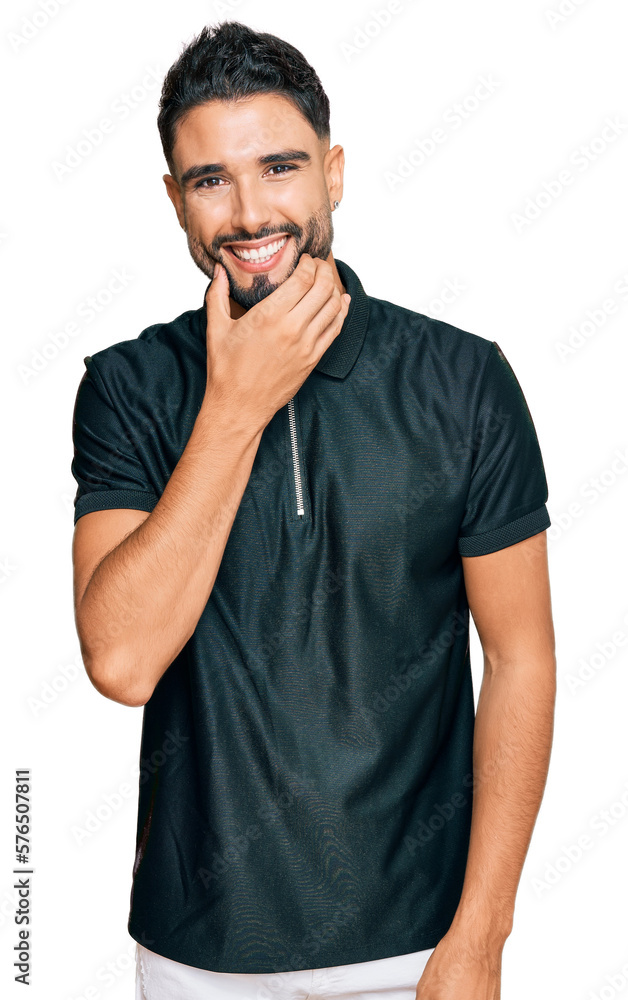 Young man with beard wearing sportswear looking confident at the camera smiling with crossed arms and hand raised on chin. thinking positive. Young man with beard wearing sportswear looking confident at the camera smiling with crossed arms and hand raised on chin. thinking positive.