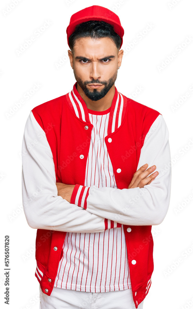 Young man with beard wearing baseball uniform skeptic and nervous, disapproving expression on face with crossed arms. negative person. Young man with beard wearing baseball uniform skeptic and nervous, disapproving expression on face with crossed arms. negative person.