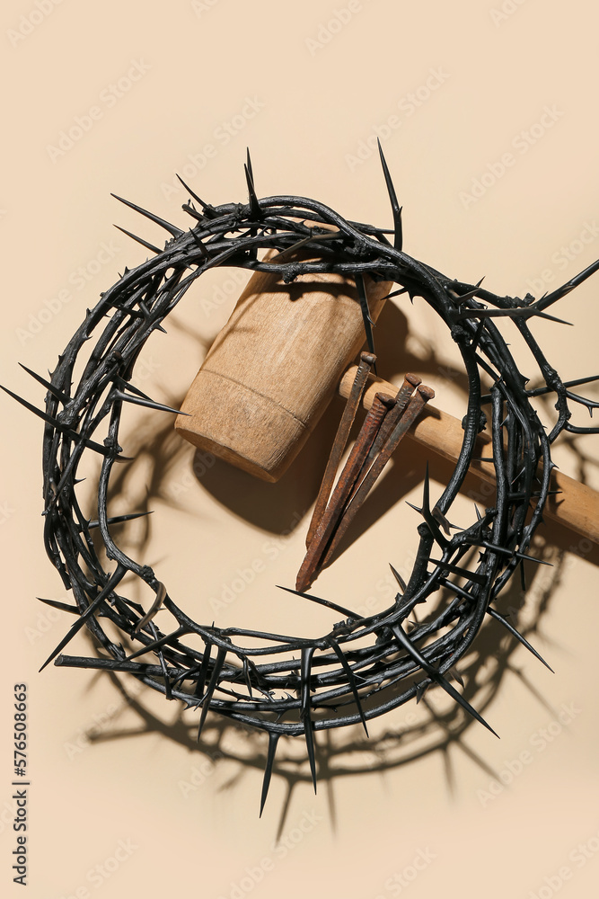 Crown of thorns, mallet and nails on beige background