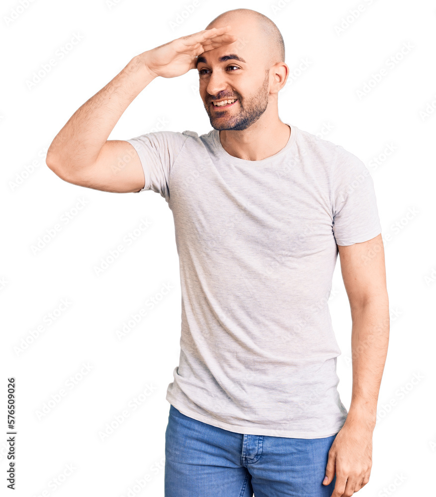 Young handsome man wearing casual t shirt very happy and smiling looking far away with hand over head. searching concept. Young handsome man wearing casual t shirt very happy and smiling looking far away with hand over head. searching concept.
