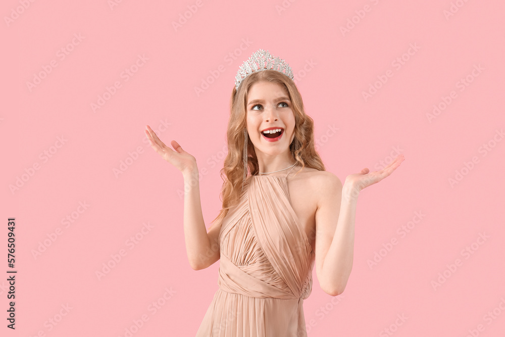 Happy teenage girl in tiara and prom dress on pink background Happy teenage girl in tiara and prom dress on pink background