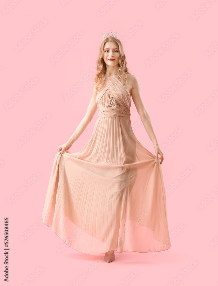 Teenage girl in crown and prom dress on pink background Teenage girl in crown and prom dress on pink background