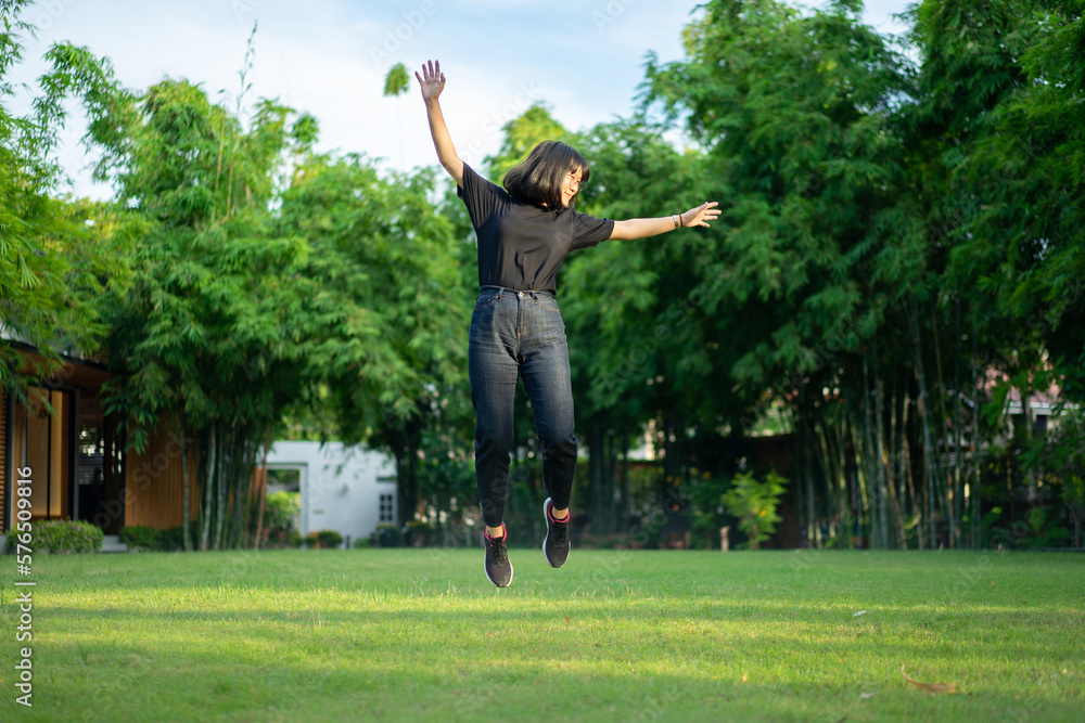 Asian short hair Woman is Joyful Jumping on the grass field garden. Asian short hair Woman is Joyful Jumping on the grass field garden.