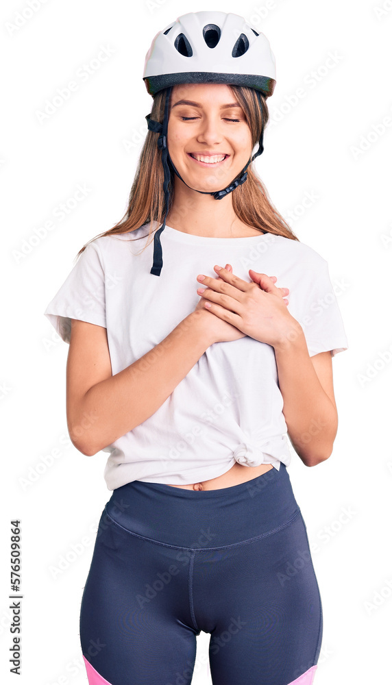 Young beautiful girl wearing bike helmet smiling with hands on chest with closed eyes and grateful gesture on face. health concept.