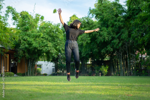 Asian short hair Woman is Joyful Jumping on the grass field garden.