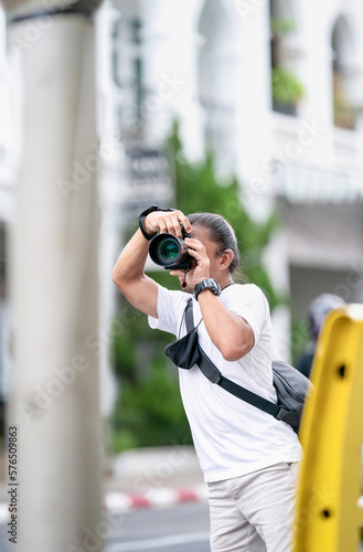Professional Asian Camera man focus on the image with his mirrorless camera beside the street outdoor field. photo