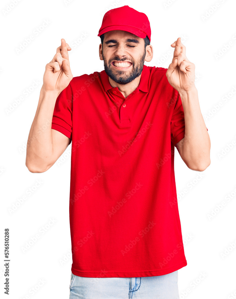 Young handsome man with beard wearing delivery uniform gesturing finger crossed smiling with hope and eyes closed. luck and superstitious concept.