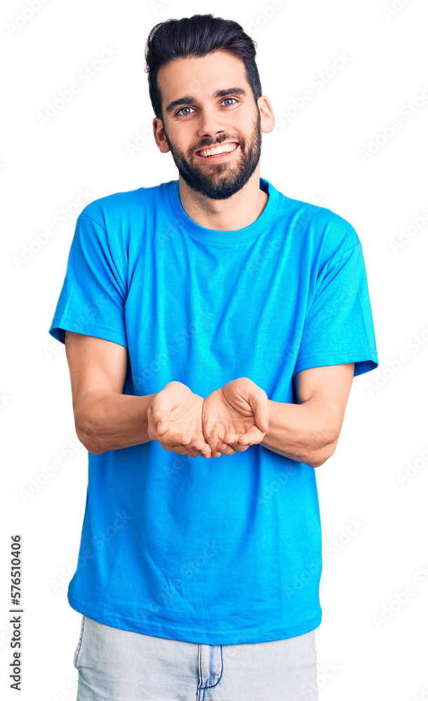Young handsome man with beard wearing casual t-shirt smiling with hands palms together receiving or giving gesture. hold and protection Young handsome man with beard wearing casual t-shirt smiling with hands palms together receiving or giving gesture. hold and protection