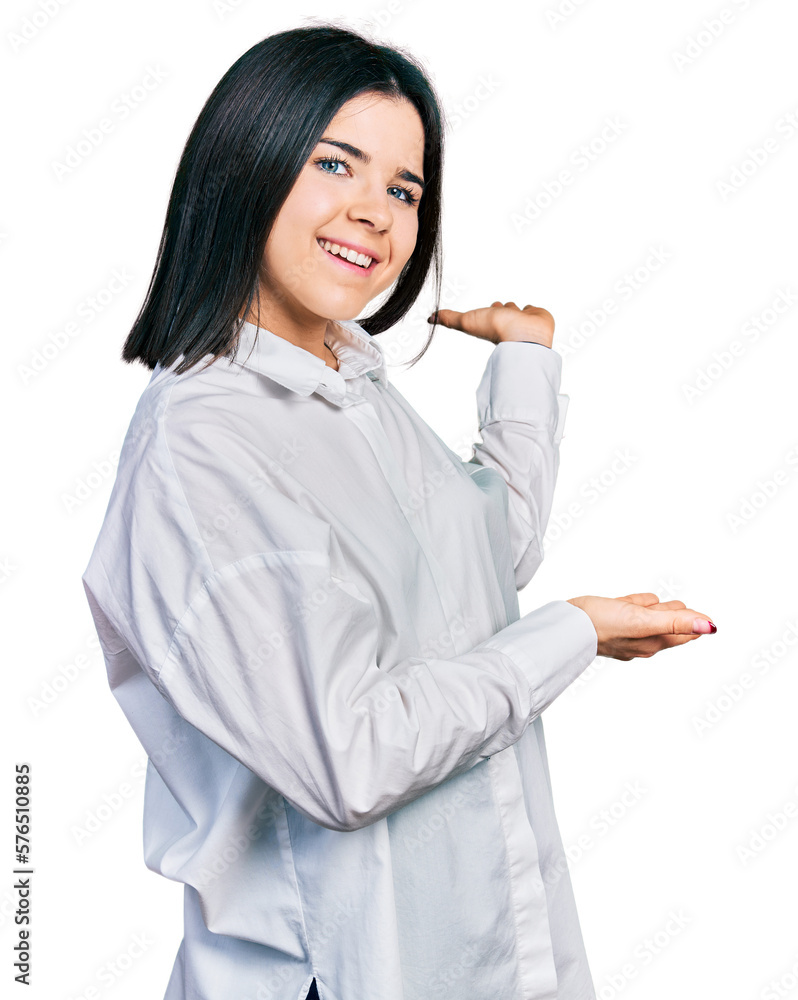 Young brunette woman with blue eyes wearing oversize white shirt inviting to enter smiling natural with open hand Young brunette woman with blue eyes wearing oversize white shirt inviting to enter smiling natural with open hand