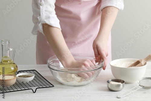 Billede på lærred Woman kneading dough at white wooden table in kitchen, closeup