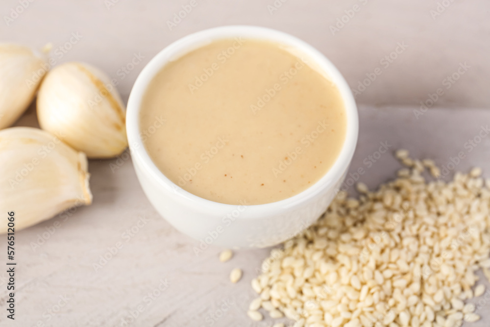 Bowl of tasty tahini, sesame seeds and garlic on table, closeup Bowl of tasty tahini, sesame seeds and garlic on table, closeup