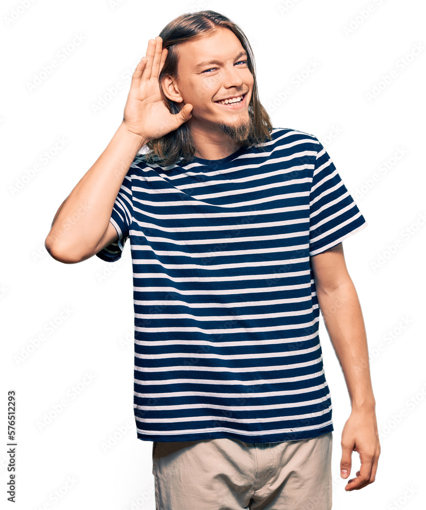 Handsome caucasian man with long hair wearing casual striped t-shirt smiling with hand over ear listening an hearing to rumor or gossip. deafness concept. Handsome caucasian man with long hair wearing casual striped t-shirt smiling with hand over ear listening an hearing to rumor or gossip. deafness concept.