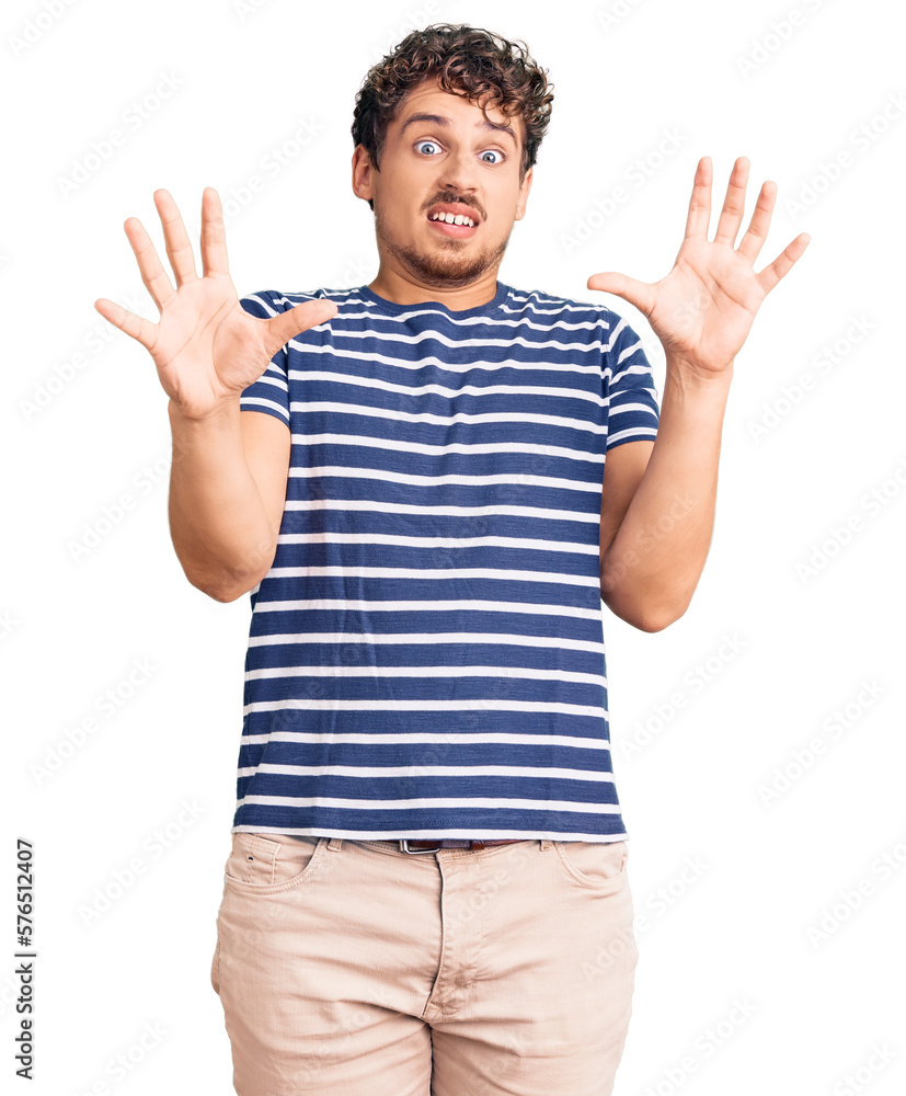 Young handsome man with curly hair wearing casual clothes afraid and terrified with fear expression stop gesture with hands, shouting in shock. panic concept. Young handsome man with curly hair wearing casual clothes afraid and terrified with fear expression stop gesture with hands, shouting in shock. panic concept.