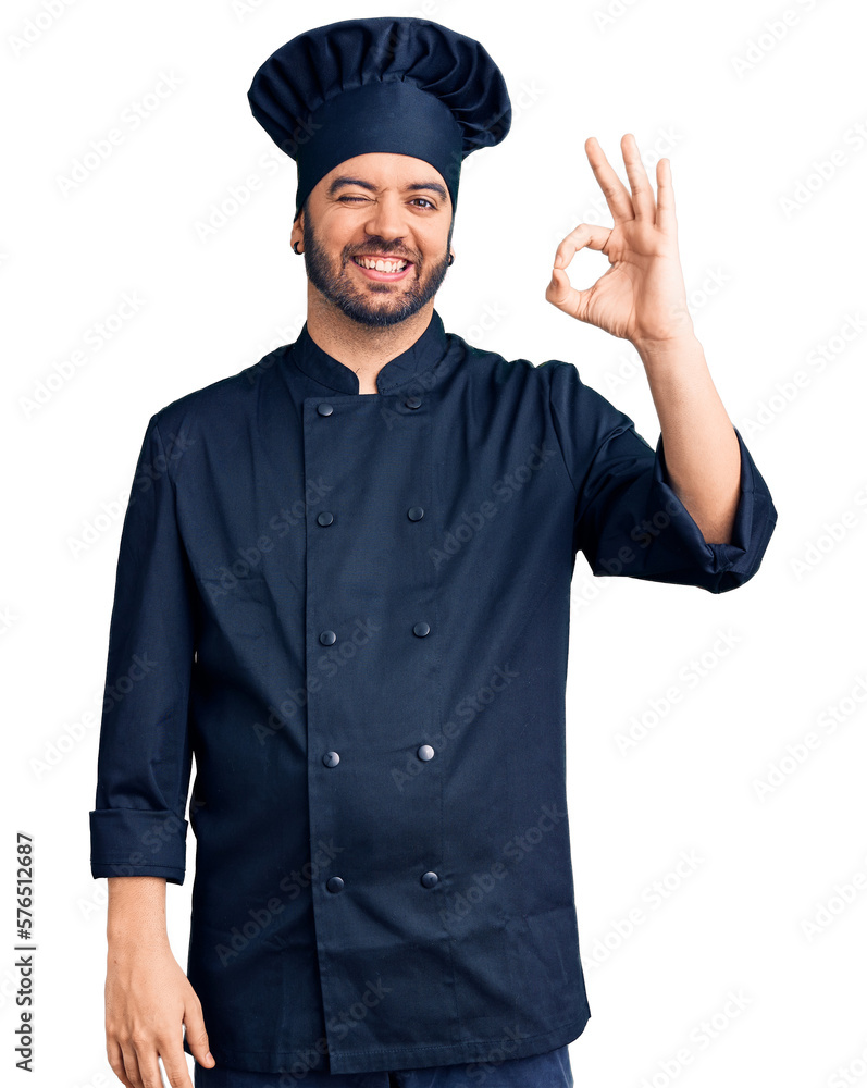 Young hispanic man wearing cooker uniform smiling positive doing ok sign with hand and fingers. successful expression. Young hispanic man wearing cooker uniform smiling positive doing ok sign with hand and fingers. successful expression.