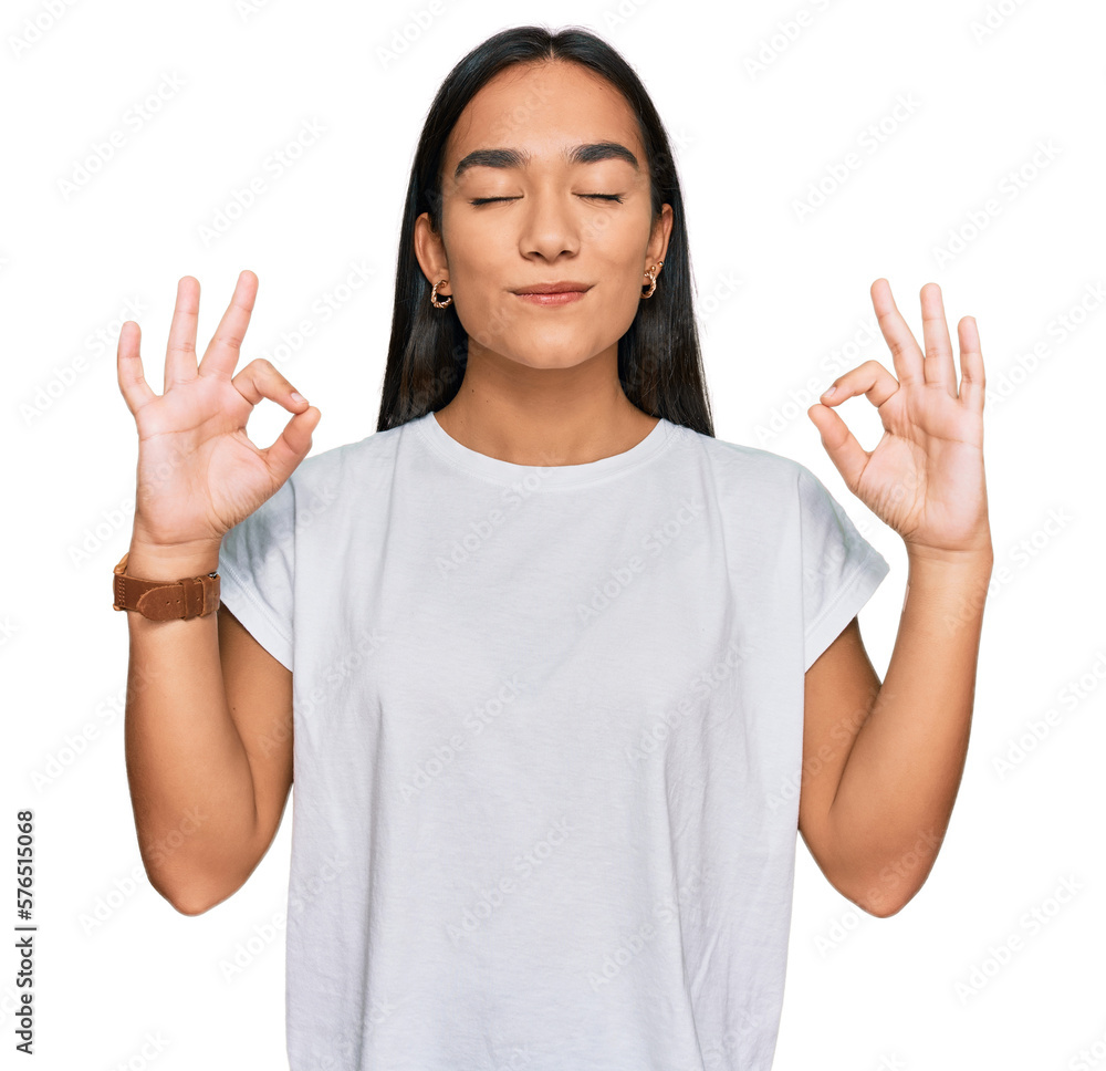 Young asian woman wearing casual white t shirt relax and smiling with eyes closed doing meditation gesture with fingers. yoga concept. - obrazy, fototapety, plakaty 