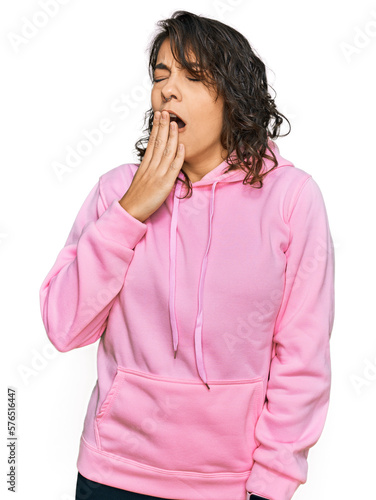 Young hispanic woman wearing casual sweatshirt bored yawning tired covering mouth with hand. restless and sleepiness.